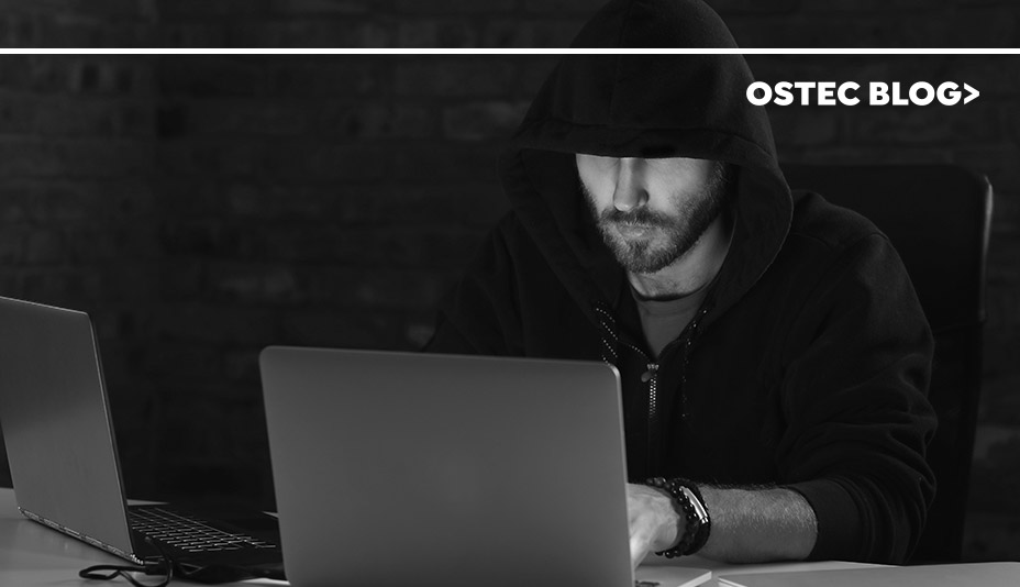 Homem sentado no escuro na frente de um laptop, provocando ataques cibernéticos.