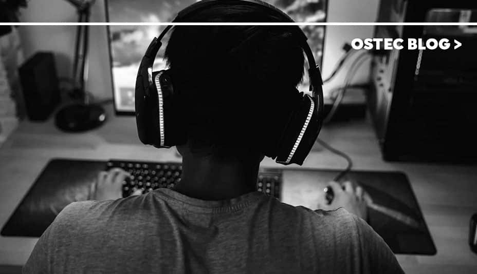 Menino com fone de ouvido e em frente a um computador jogando jogos online