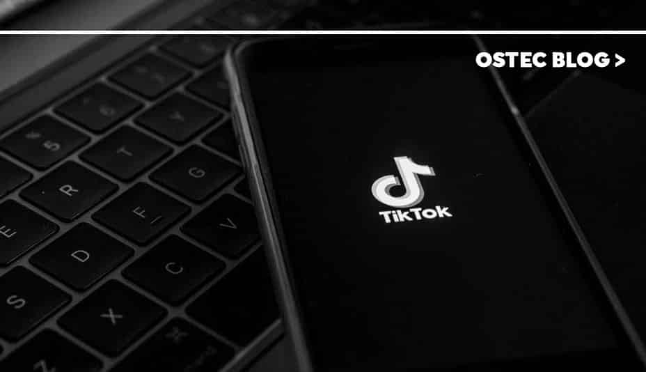 Celular com ícone do TikTok em sua tela sobre um notebook.